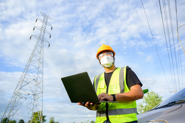 Sticker - Asian male electrical engineer stands holding a laptop computer at a power plant running and plots to inspect high-voltage poles at a power station.