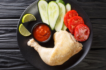 Canvas Print - Tasty Ayam pop chicken with vegetables and sauce close up in the plate on the table. Horizontal top view from above