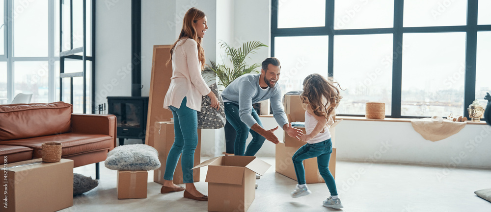 Happy young family smiling and unboxing their stuff while moving into a new apartment