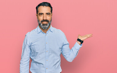 Sticker - Middle aged man with beard wearing business shirt smiling cheerful presenting and pointing with palm of hand looking at the camera.