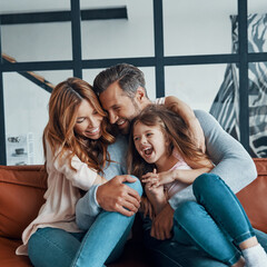 Happy young family with little girl preschool age smiling while bonding together at home