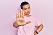 Beautiful hispanic woman with short hair wearing casual pink t shirt moving away hands palms showing refusal and denial with afraid and disgusting expression. stop and forbidden.