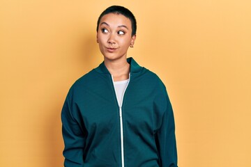 Wall Mural - Beautiful hispanic woman with short hair wearing sporty jacket smiling looking to the side and staring away thinking.