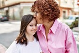 Fototapeta Miasto - Mature mother and down syndorme daughter smiling happy and friendly outdoors, mom kissing girl forehead