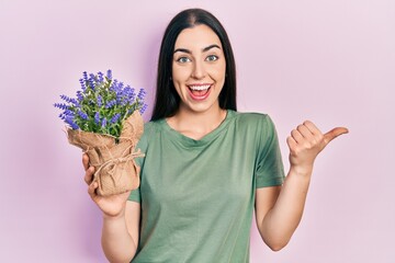 Sticker - Beautiful woman with blue eyes holding lavender plant pointing thumb up to the side smiling happy with open mouth