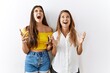 © Krakenimages.com - Mother and daughter together standing together over isolated background crazy and mad shouting and yelling with aggressive expression and arms raised. frustration concept.