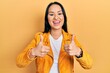 © Krakenimages.com - Beautiful hispanic woman with nose piercing wearing yellow leather jacket success sign doing positive gesture with hand, thumbs up smiling and happy. cheerful expression and winner gesture.