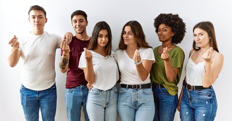 Canvas Print - Group of young friends standing together over isolated background doing money gesture with hands, asking for salary payment, millionaire business