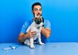 Handsome hispanic veterinary man with beard checking dog health hand on mouth telling secret rumor, whispering malicious talk conversation