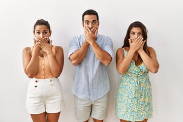 Sticker - Group of young hispanic people standing over isolated background shocked covering mouth with hands for mistake. secret concept.