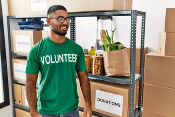 Sticker - Young indian man volunteer holding donations box looking away to side with smile on face, natural expression. laughing confident.