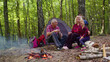 © Andrii Iemelianenko - Senior elderly grandmother grandfather granddaughter telling funny stories fairy tales over campfire in wood. Old man woman and child girl kid tourists having camping in forest. Active rest of family