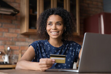 Happy African American Shopper Using Computer And Credit Card For Buying On Internet, Shopping Online, Looking Away, Smiling, Thinking Over Purchases, Paying Bills On Financial Banking App