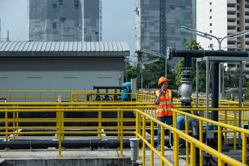 Women engineer check panel broad of booster pump at water plant. Worker taking note using pen and paper. Women engineer checks equipment at work and records readings.