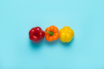 Wall Mural - Three fresh bright sweet peppers on a blue background. Top view, flat lay