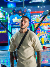 Portrait Of An Attractive Spanish Man With Tattoos In An Amusement Arcade