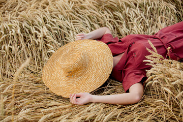 Sticker - young woman in red dress with hat is lying on spikelets of wheat field