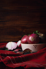 Wall Mural - Closeup of the red onions in the bowl on a fabric against the wooden background