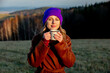 Young woman with cup of coffee stay near wood in sunset time