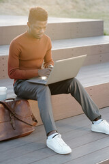 Poster - Contemporary African businessman or student with laptop networking outdoors