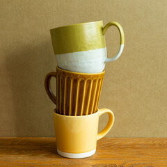 Wall Mural - Stack of mug cup on wooden table. brown wall background. copy space