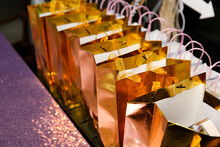 A View Of Several Golden Goodie Bags On A Table, Seen At A Reception Event.