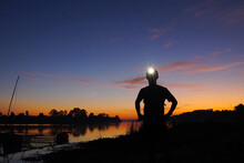 A Trail Runner Standing With A Headlamp On His Head With Silhouette Sky