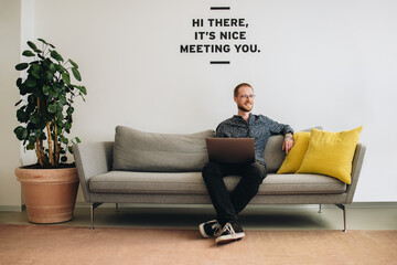 Wall Mural - Man sitting at lobby with laptop looking away