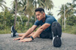 © Charnchai saeheng - young man stretching in the park before running. Young man workout before fitness training at the park. Healthy and exercise young man warming up on the road in the forest.