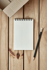 Wall Mural - open blank spiral notebook with open empty cardboard box and black pencil on wood table, online shop