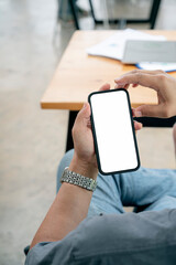 Wall Mural - cropped shot of man hand holding blank screen smartphone while sitting at living room. vertical view