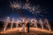 © Елена Кузина - A couple in wedding dresses on the background of fireworks at night.