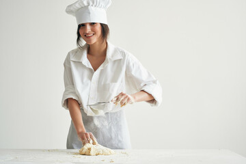 Wall Mural - woman in chef's uniform baker rolling dough kitchen work