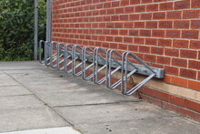 Empty Bike Rack, Parking For Bicycles Against A Red Brick Wall