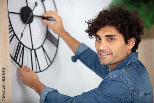 young man hanging clock on a wall at home