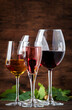 Wine tasting. Red, white, rose and champagne - still and sparkling wines sin glasses on vintage wooden table background