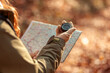 Woman holding a compass and reading a map while hiking