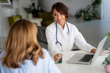 Female doctor consulting her patient while sitting at desk in doctor's office