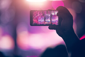 Person holding modern smartphone on a concert.