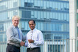 © DragonImages - Positive mature entrepreneur shaking hand of investor after meeting, office building or skyscraper in background