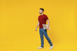 Full length smiling happy young man in red tshirt casual clothes hold closed laptop pc computer work look aside isolated on plain yellow color wall background studio portrait People lifestyle concept