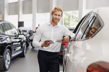 Canvas Print - Man customer male buyer client in white shirt read car papers documents agreement look camera choose auto want buy new automobile in showroom vehicle dealership store motor show indoor Sales concept