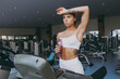 Young sweating skinny strong sporty athletic sportswoman woman in white sportswear warm up training run on treadmill look camera drink water in gym indoor Workout sport motivation lifestyle concept.