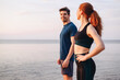 Profile couple young two friend strong sporty sportswoman sportsman woman man in sport clothes warm up train stand akimbo do exercise on sand sea ocean beach outdoor on seaside in summer day morning.