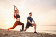 © ViDi Studio - Full size sunlit couple young two friend sporty sportswoman sportsman woman man in sport clothes warm up training do lunges do exercise on sand sea ocean beach outside on seaside in summer day morning