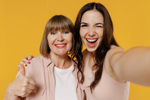Close Up Two Young Smiling Fun Daughter Mother Together Couple Women In Casual Beige Clothes Do Selfie Shot Pov On Mobile Phone Show Thumb Up Gesture Blink Isolated On Plain Yellow Background Studio
