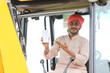 © Niks Ads - Indian man working with heavy earth moving machinery and showing smartphone screen.