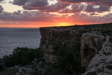 Poster - Reddish sky and clouds during a peaceful sunset from the high limestone cliffs of Mellieha, Malta.