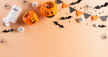 Halloween Decorations Made From Pumpkin, Paper Bats And Black Spider On Pastel Orange Background. Flat Lay, Top View With Copy Space For Text.