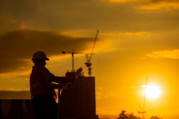 Wall Mural - silhouette of engineer and construction site background at sunset